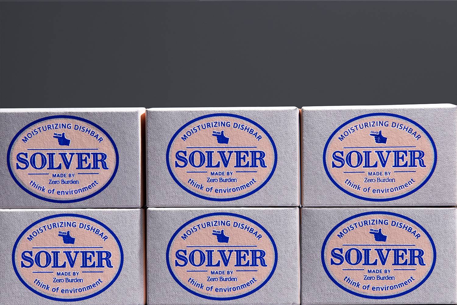 여섯 개의 Solver 디쉬바 패키지가 정렬되어 있는 장면으로, 각 패키지의 앞면에는 'Solver'라는 제품명과 함께 손가락 모양 아이콘이 인쇄되어 있음. 패키지의 균일한 배치와 통일된 디자인이 브랜드의 정체성을 강조하며, 크라프트 용지의 질감이 고급스러움을 더해줌